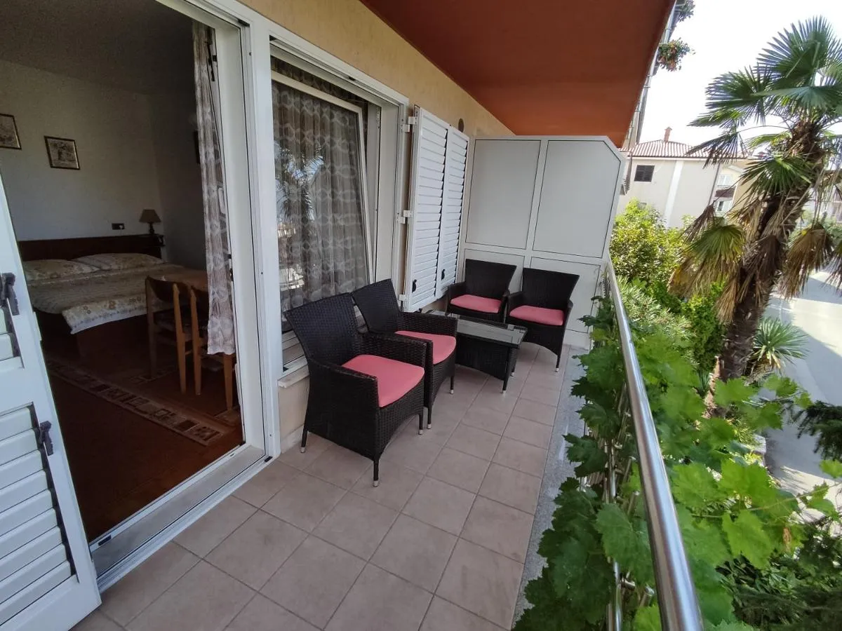 Terasa apartmaja Brin z vrtnimi stoli in palmo